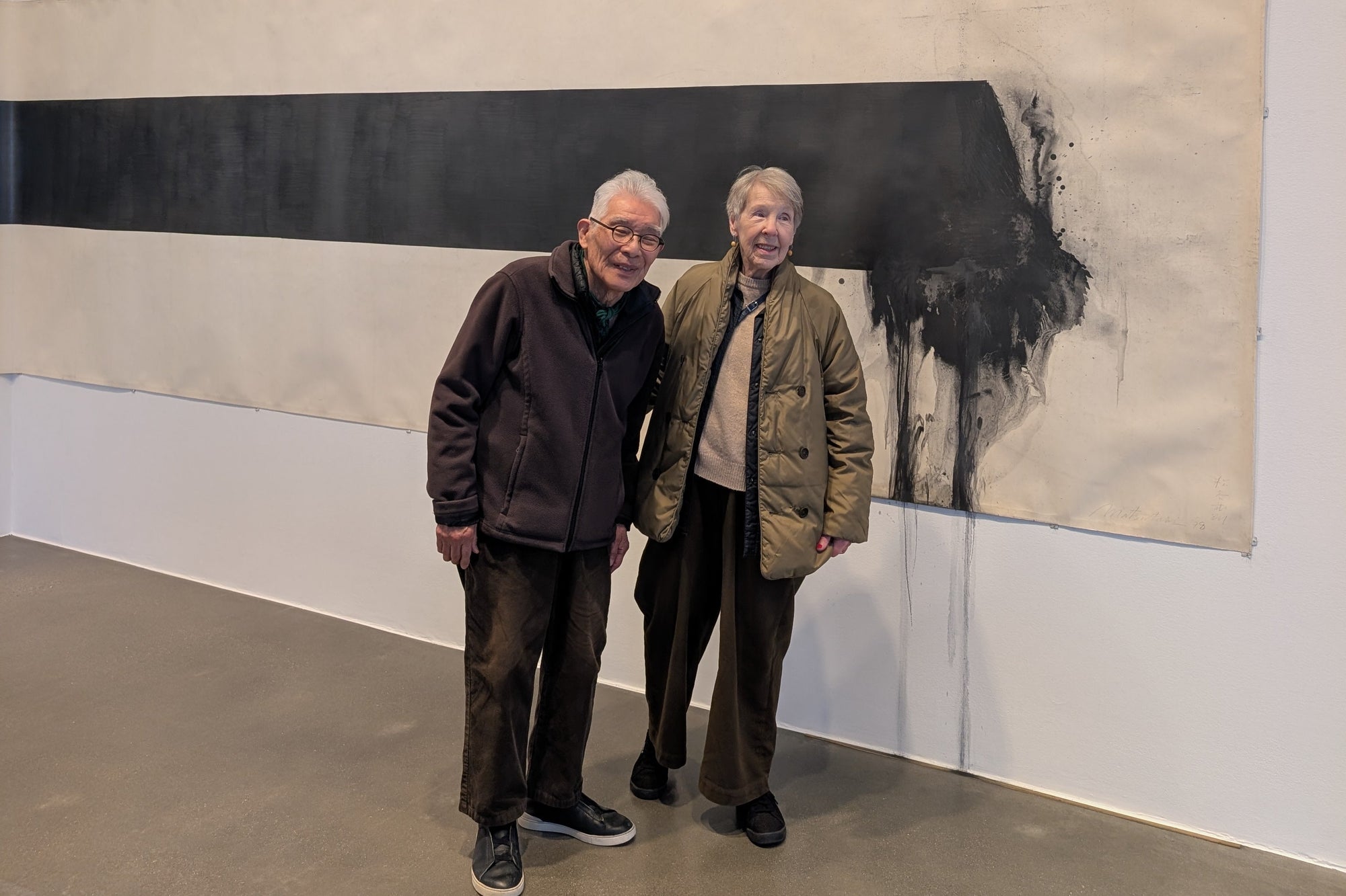 The artist Matsutani with his wife Kate Van Houten, an American artist and printmaker, whom he met in 1967 while working at the art school and studio Atelier 17 in Paris. The stand before his tream artwork at Hauser & Wirth London for this solo exhibition